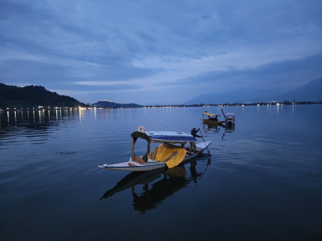 Shikara boats on Dal Lake at dusk, reflecting Kashmir's tranquil beauty